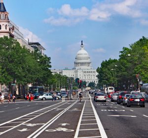 View of the street leading to capitol hill showing bike lanes and vehicles driving on the road.