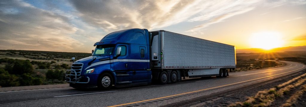 Tractor trailer driving during sunset.